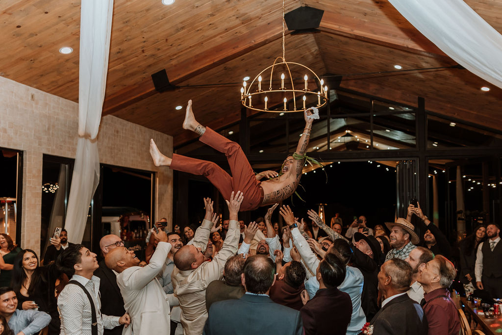 shirtless groom being thrown in the air by groomsman