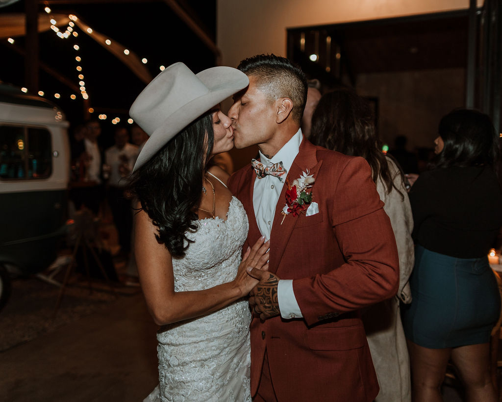 bride in cowboy hat kissing groom at night