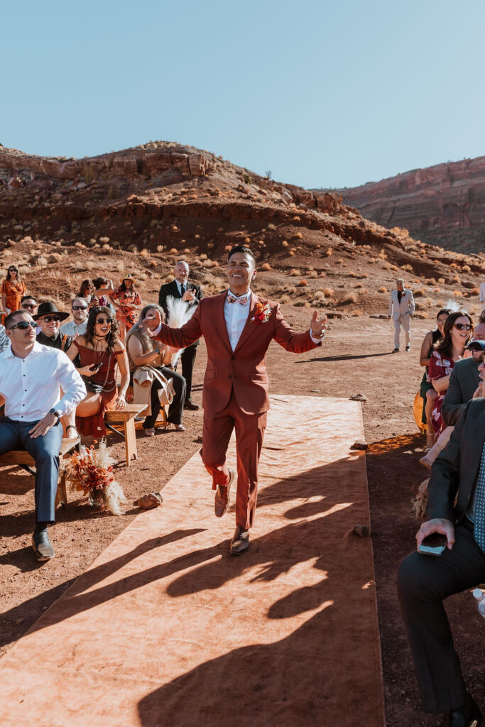 the goom walking down the isle at the red earth venue in moab utah
