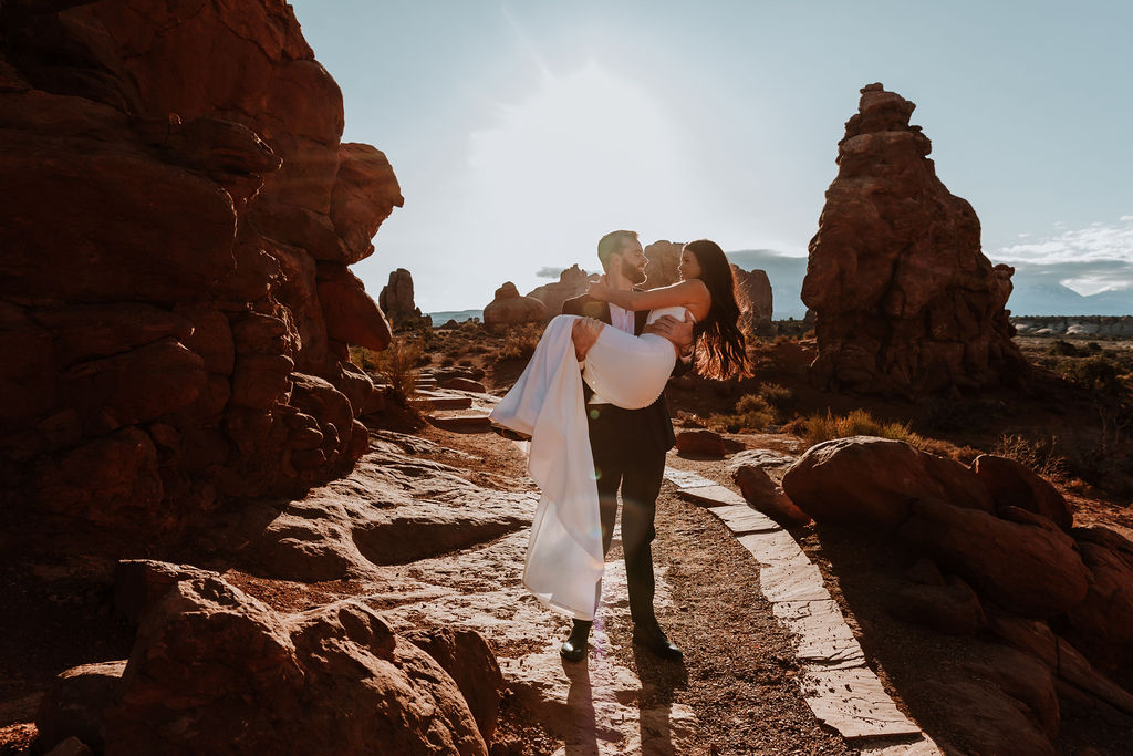 bride carries groom at Arches National Park sunrise elopement