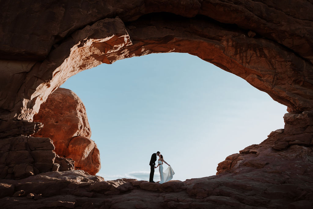 couple kisses at Arches National Park sunrise elopement