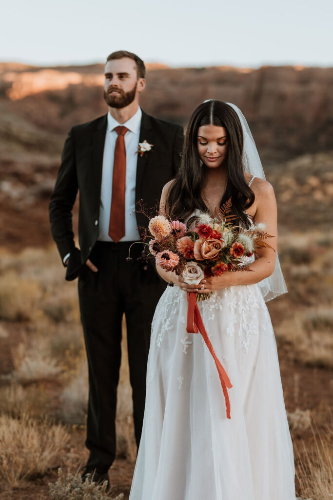 couple poses in field at Moab elopement