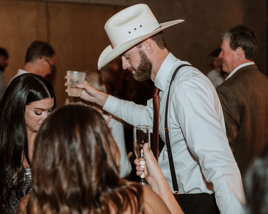 groom wears cowboy hat at wedding reception