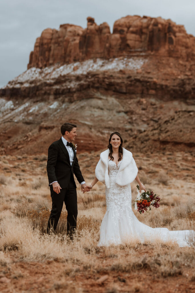 couple holds hands at outdoor winter wedding in Moab