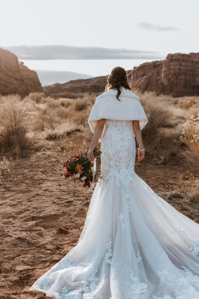 bride walks in Moab desert at outdoor wedding 