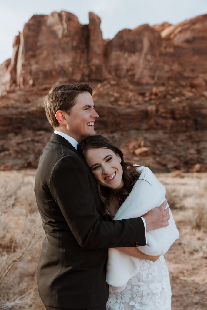 couple embraces at outdoor winter wedding in Moab