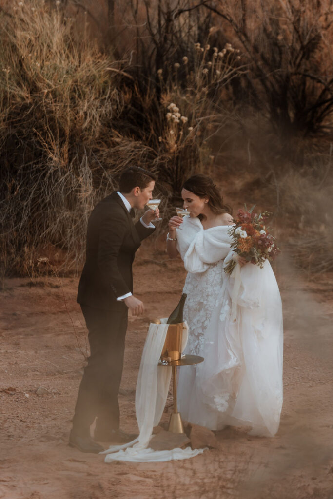 couple drinks champagne at Moab desert elopement