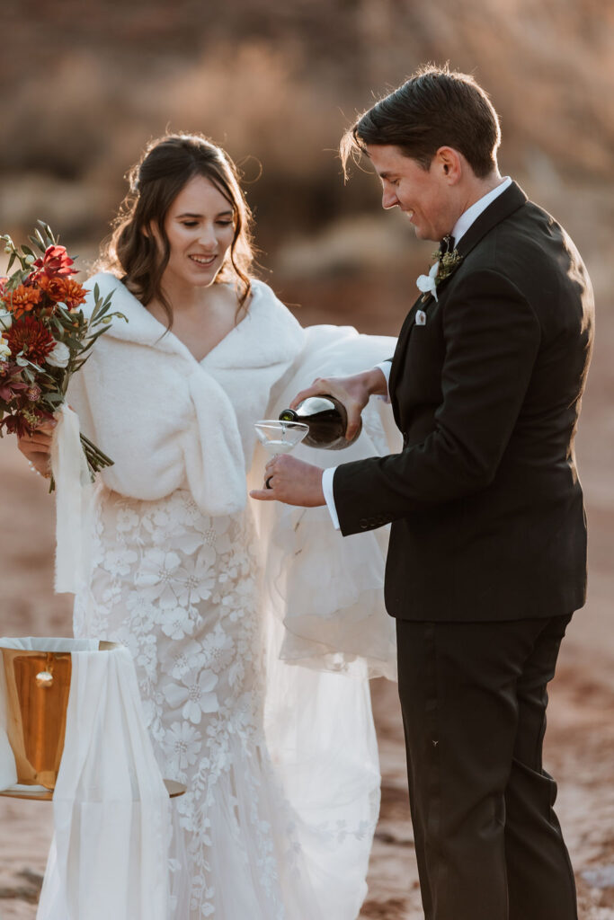couple drinks champagne at Moab desert elopement