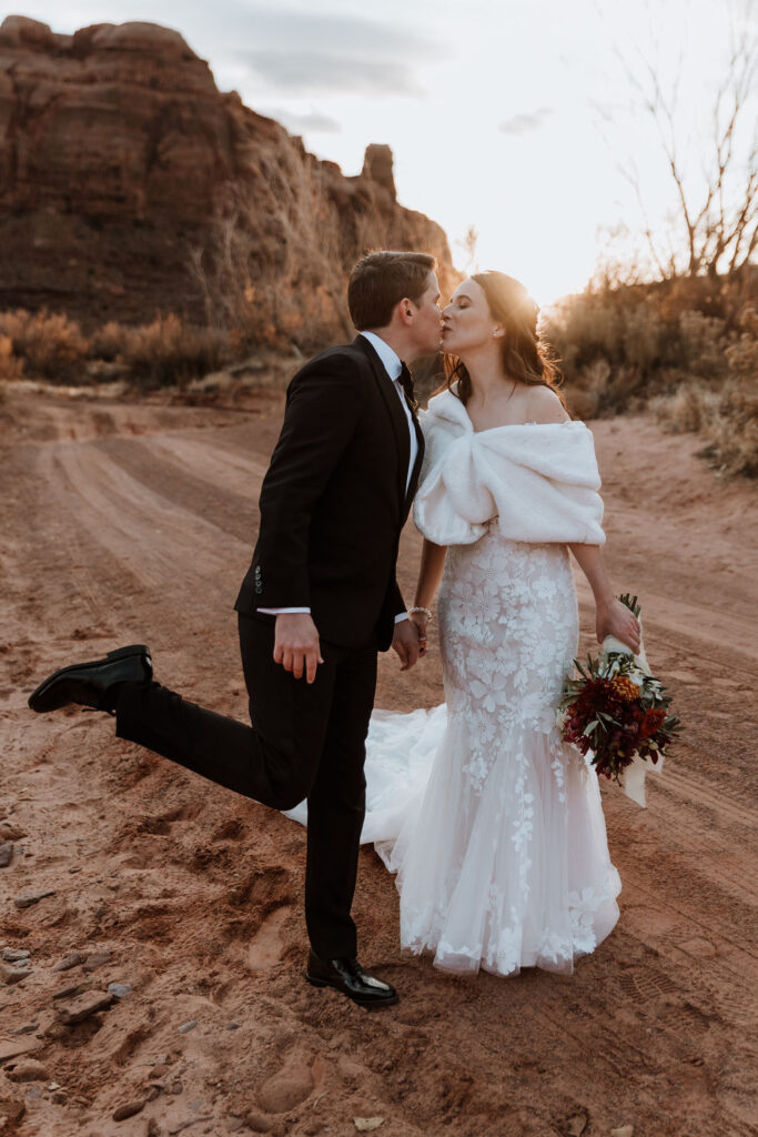 couple kisses at sunset Moab desert elopement