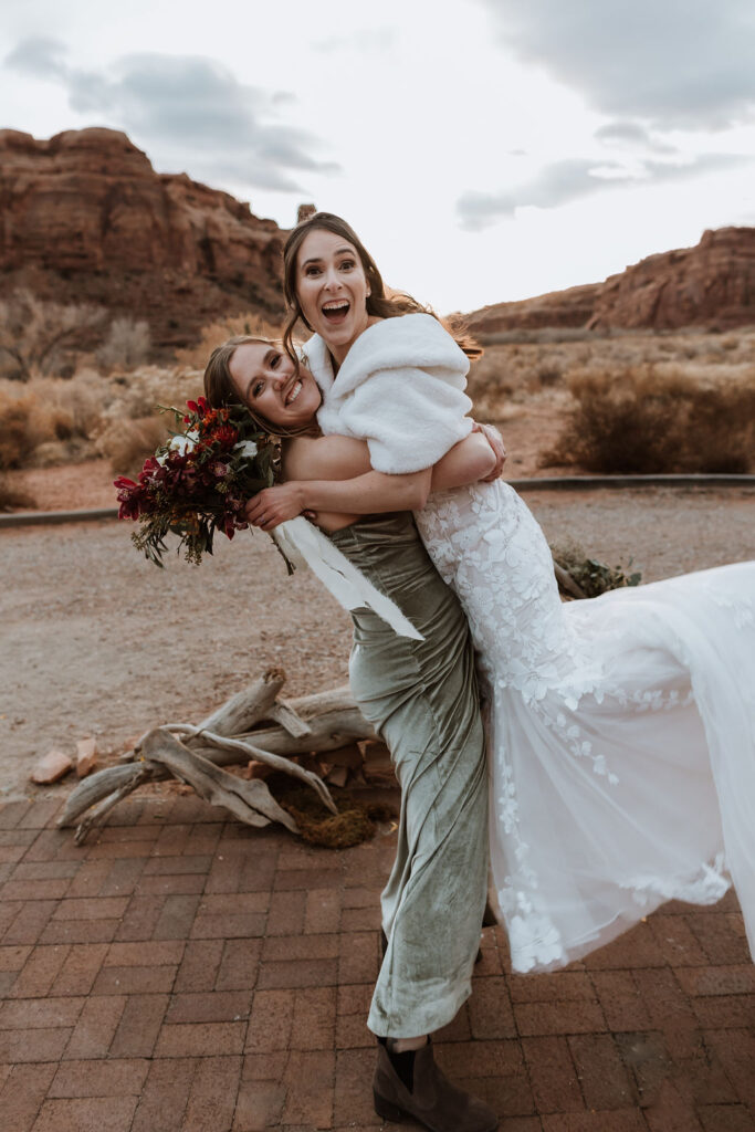 bridesmaid carries bride at outdoor Moab wedding 