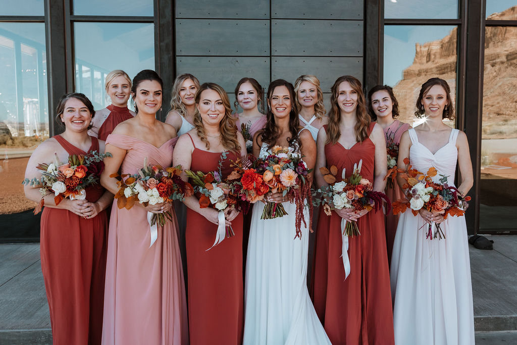 bride stands with bridesmaids holding colorful boho chic bouquets