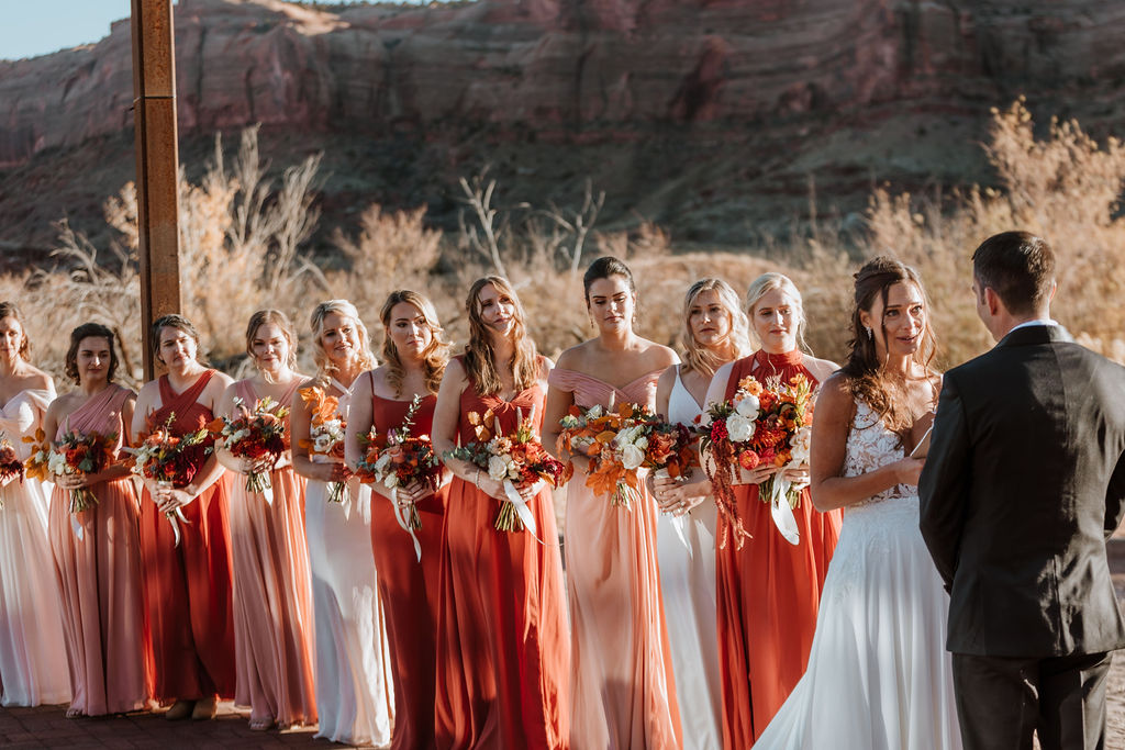 bridesmaids in different colored dresses during ceremony