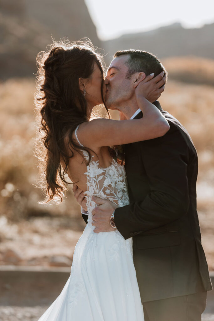 couple kisses during Moab outdoor sunset wedding 