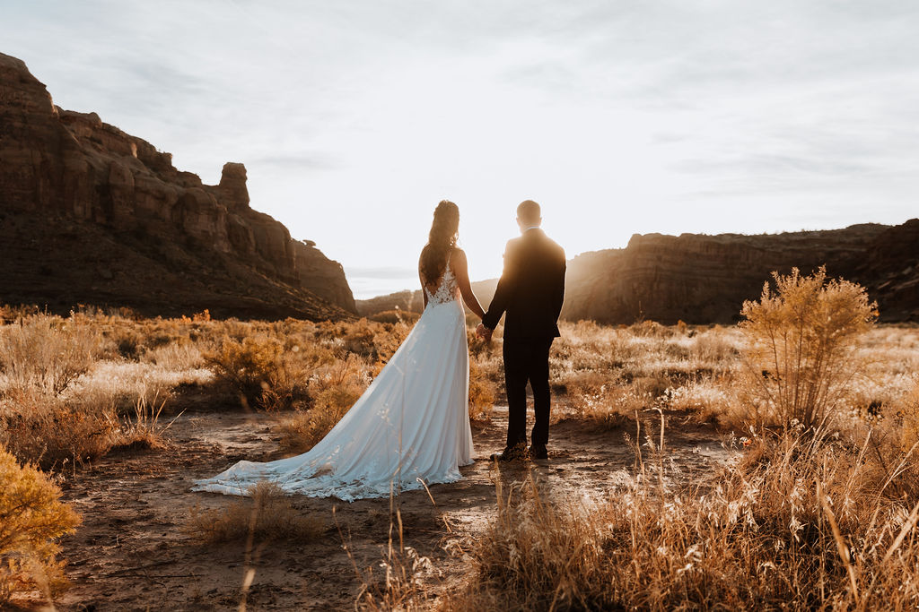 couple holds hands during sunset moab utah desert wedding