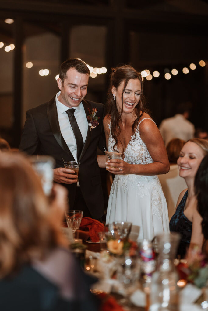couple laughs with guests during wedding reception