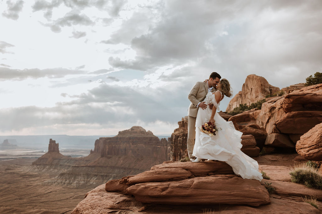 couple kisses at Moab sunset overcast elopement