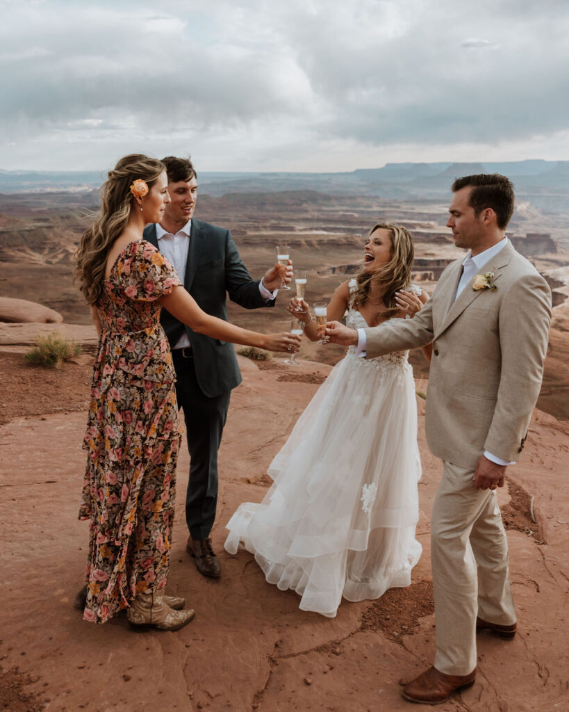couple cheers with champagne at Moab sunset elopement