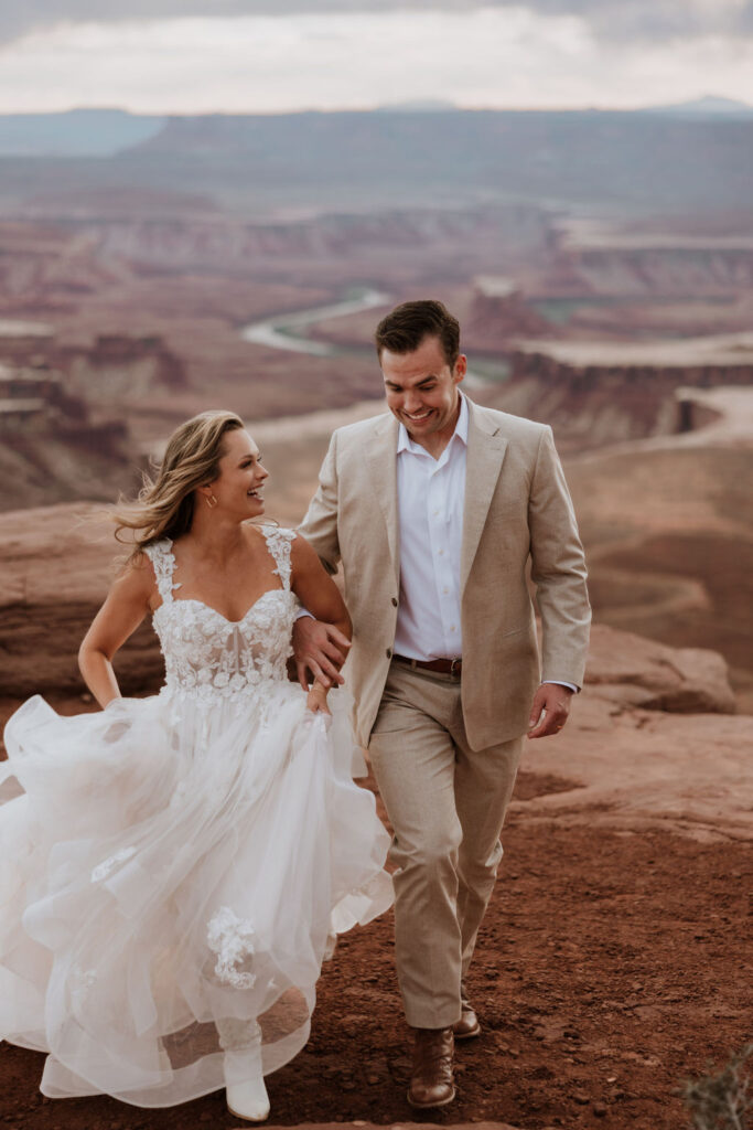 couple walks together at Moab sunset elopement