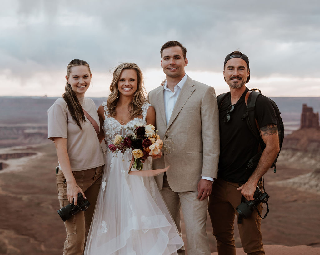 photographer stands with couple at outdoor elopement