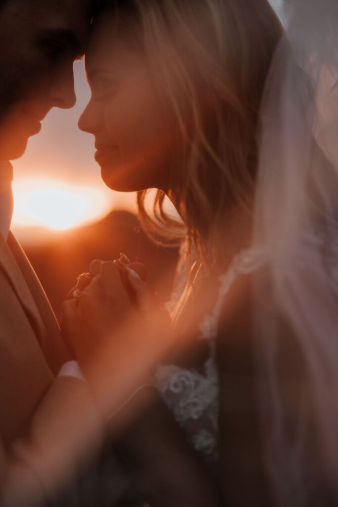 couple embraces under veil at sunset
