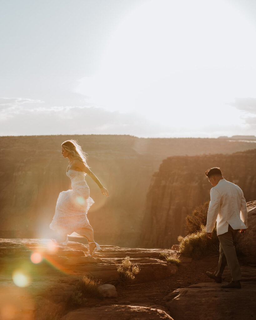 couple walks at sunset Moab overlook elopement