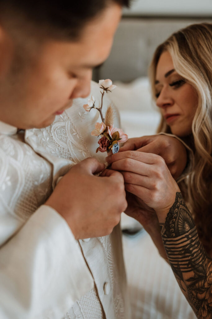 bride puts on groom's wedding boutonniere