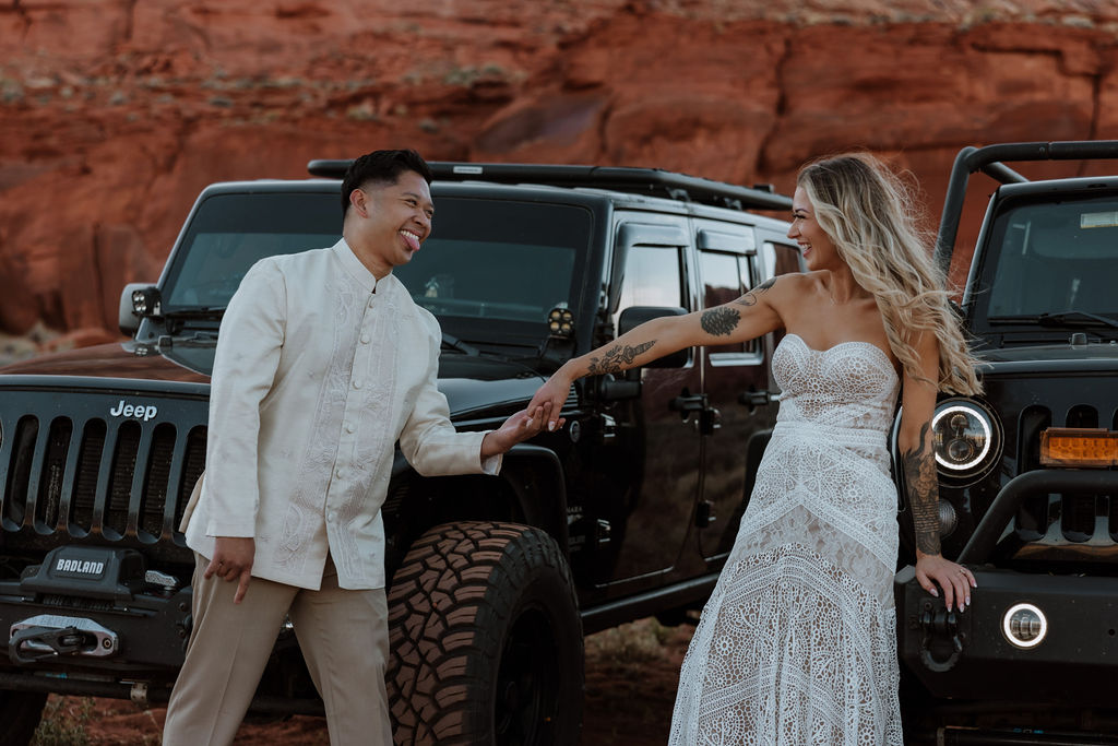 couple poses with Jeeps at Moab sunset desert elopement