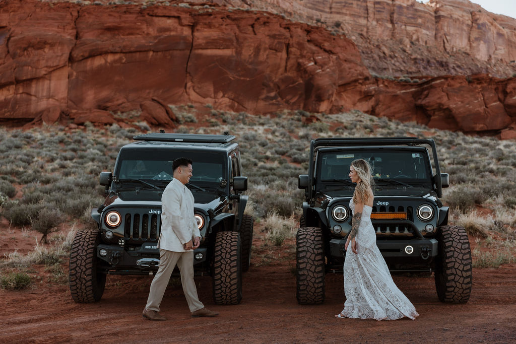 couple poses with Jeeps at Moab sunset desert elopement