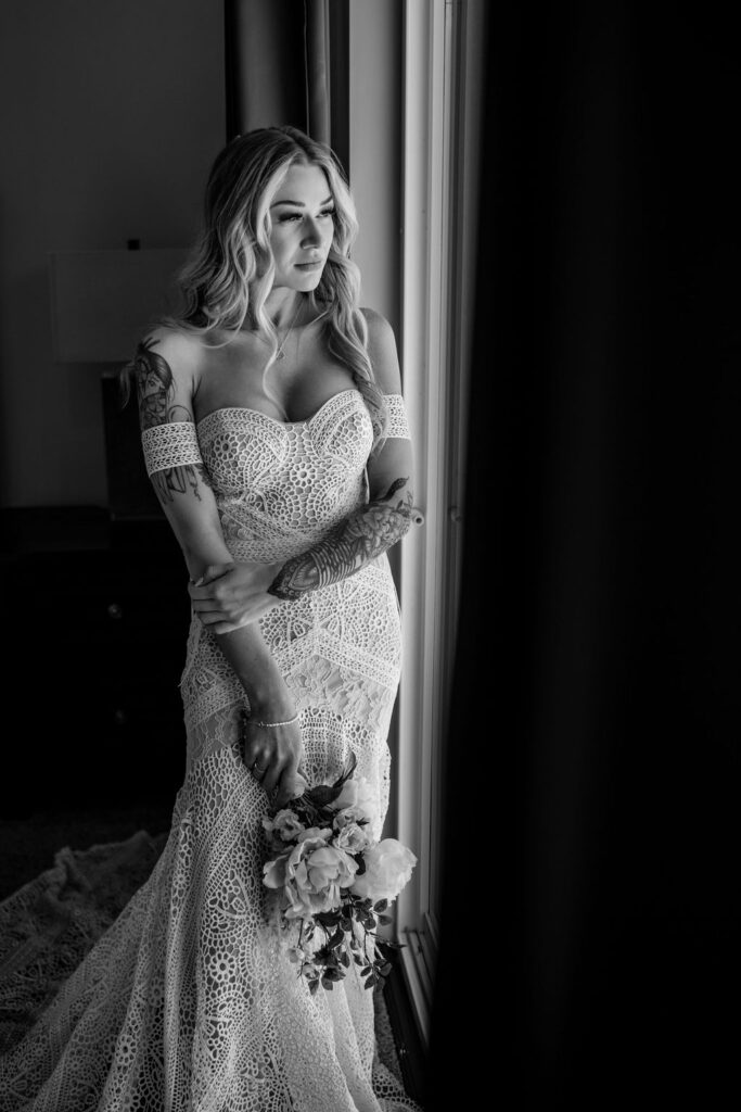 bride poses in window light holding boho wedding bouquet 