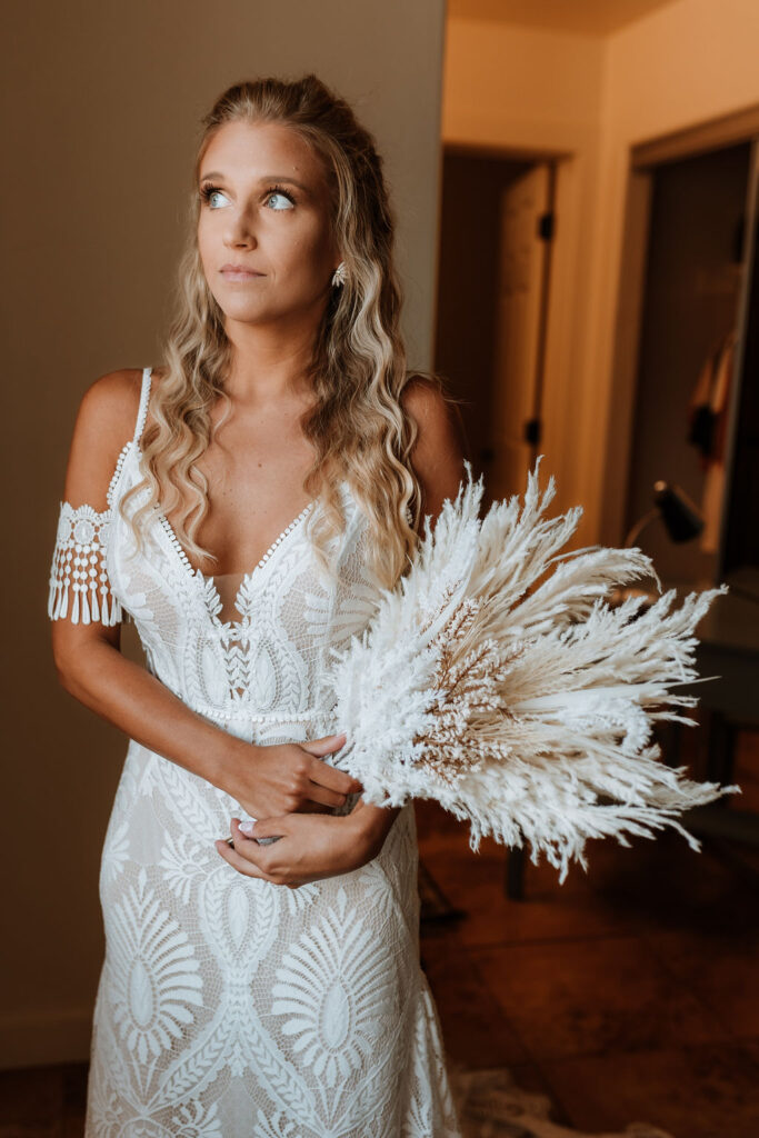 bride poses in window light holding boho wedding bouquet 