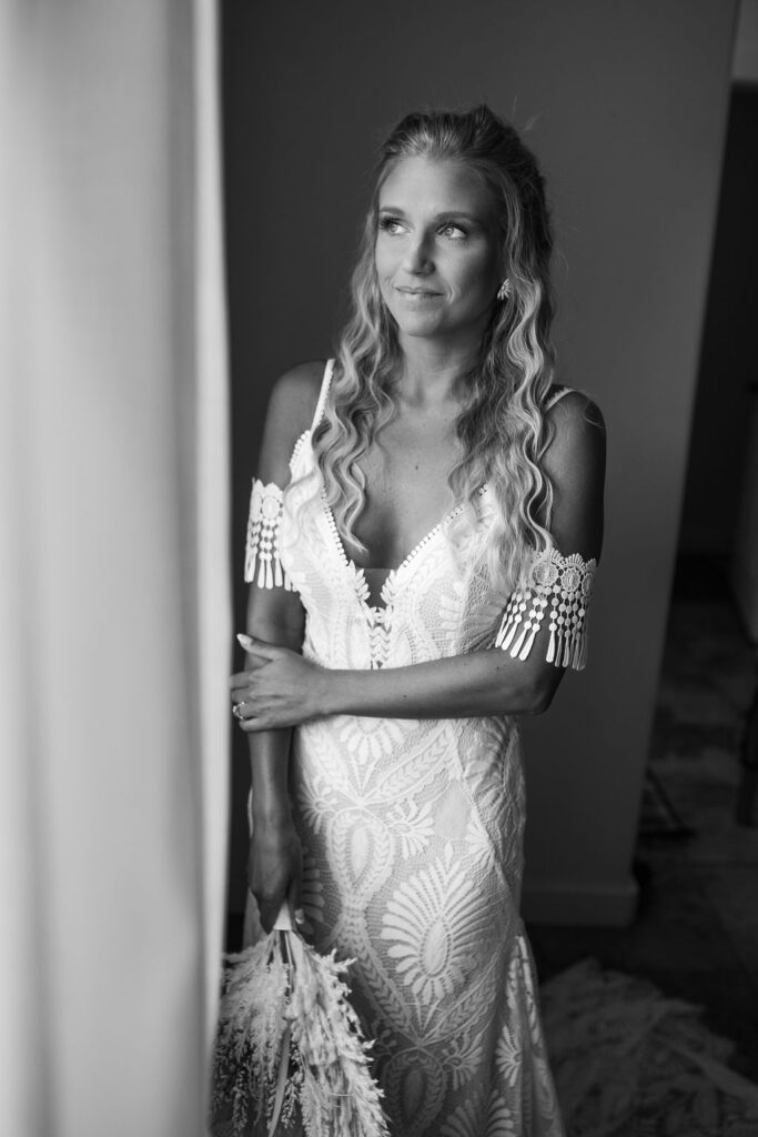 bride poses in window light holding boho wedding bouquet 