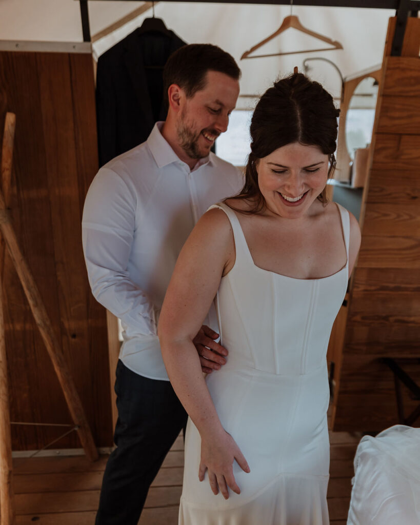 groom zips up bride's wedding dress