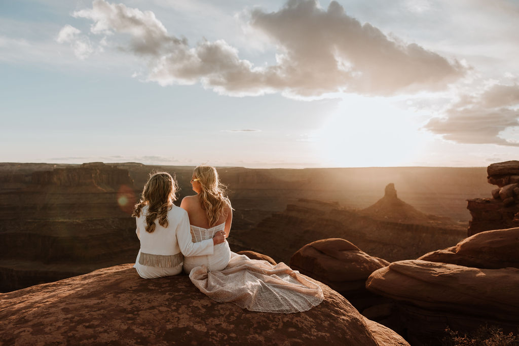 couple sits together at Dead Horse Point Overlook sunset elopement