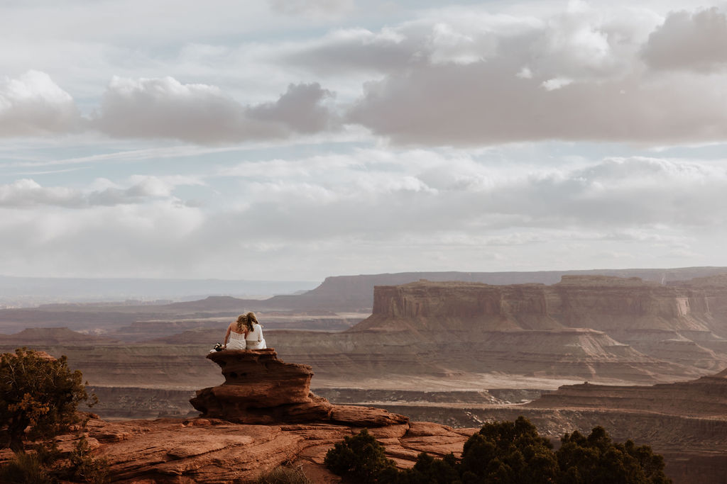 couple sits at Dead Horse Point Overlook sunset elopement
