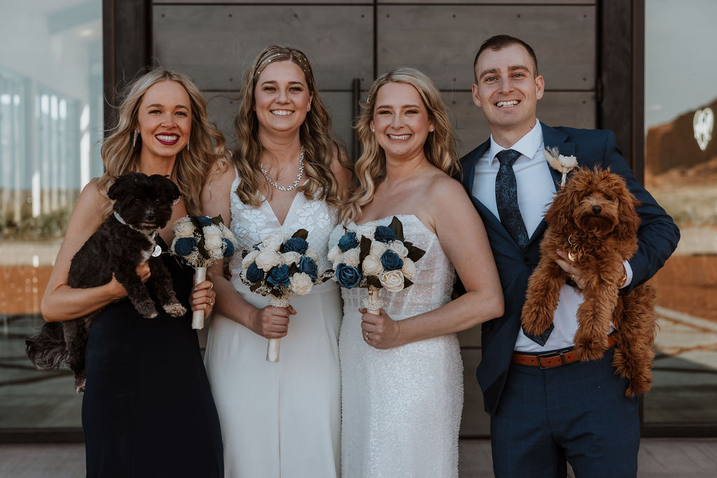 couple poses with dogs at The Red Earth Venue Moab wedding