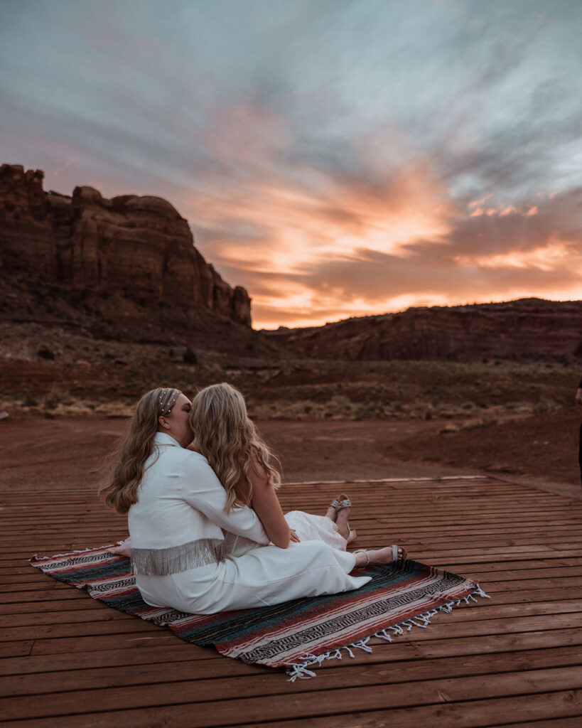 couple sits on blanket together at sunset