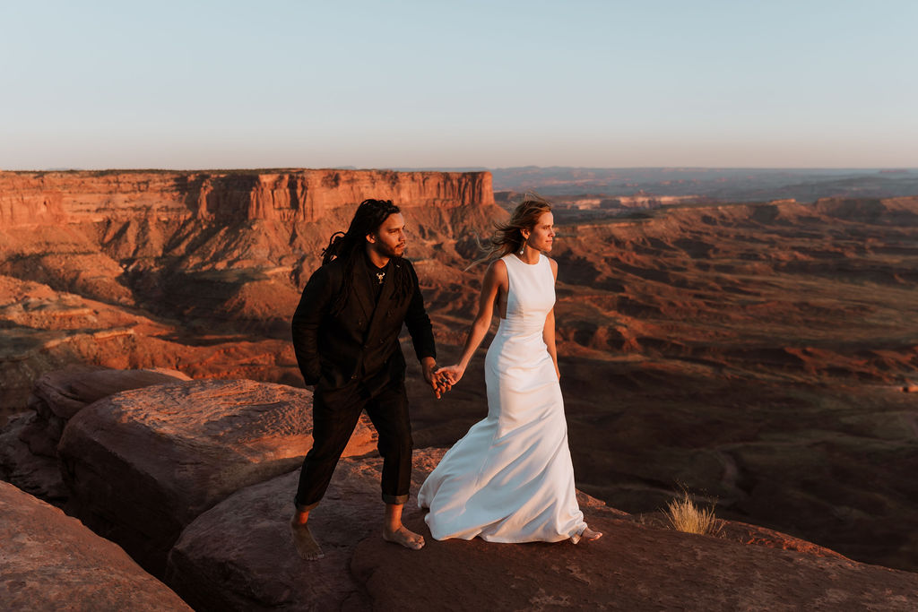 couple walks holding hands at Moab sunset desert elopement