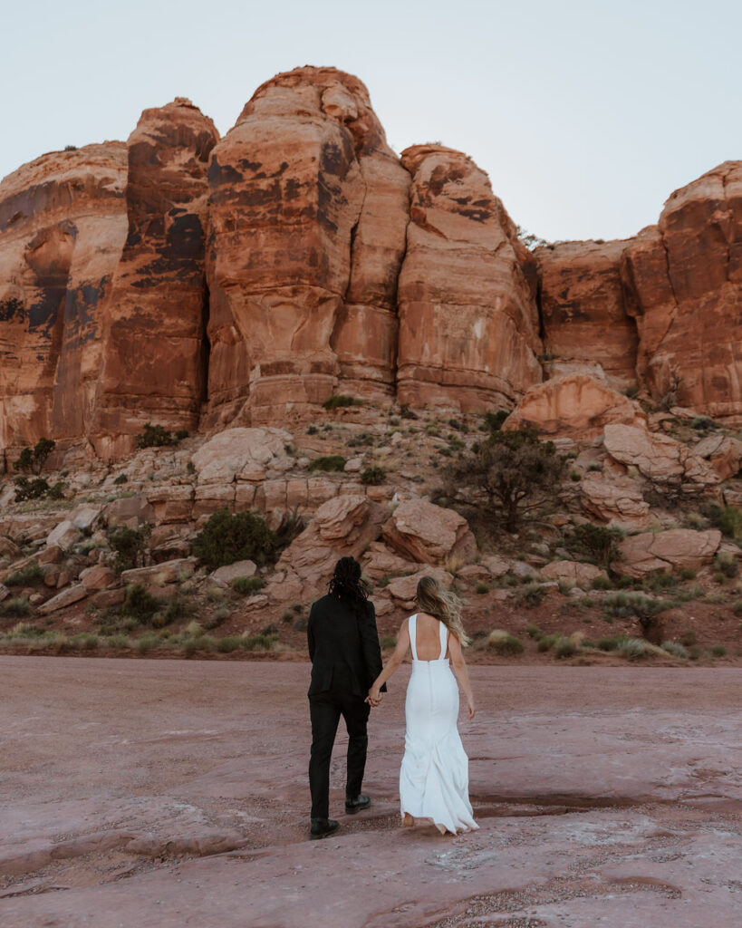 couple walks holding hands at Moab couples adventure