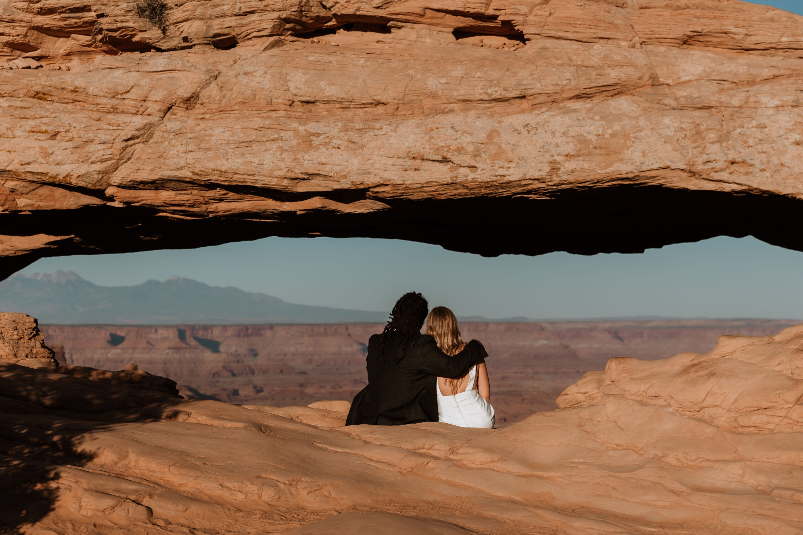 couple embraces on ledge at Moab desert elopement