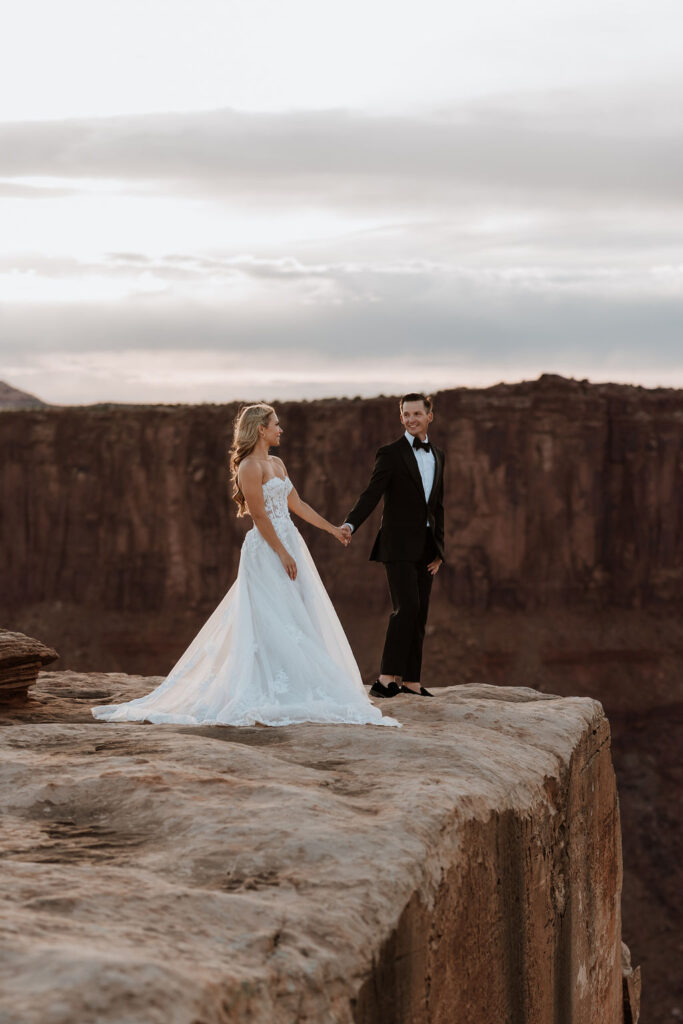 couple holds hands at Dead Horse Point Overlook
