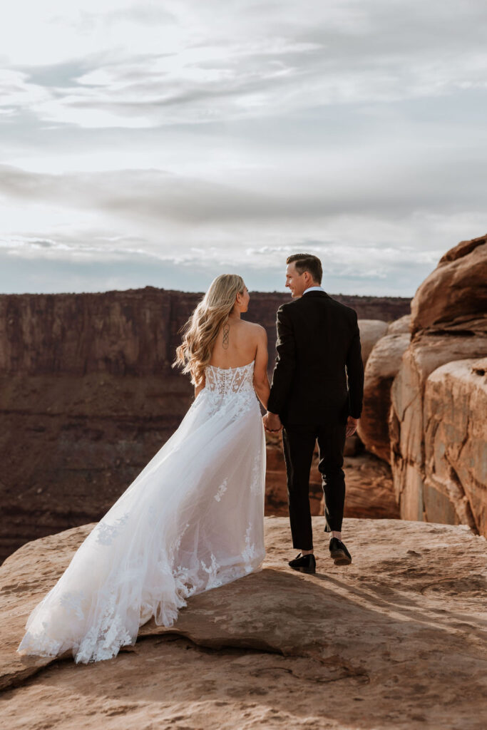 couple holds hands at Dead Horse Point Overlook