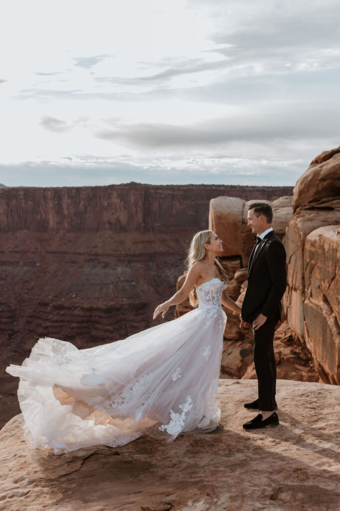 dress blows in wind at Moab sunset elopement 