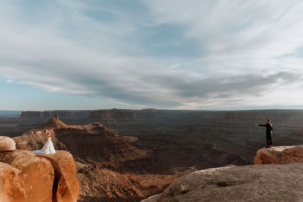 couple reaches from two overlooks at Moab elopement