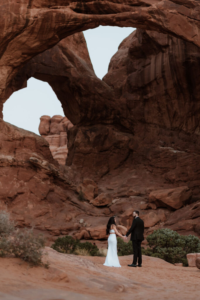 couple holds hands at Arches National Park elopement