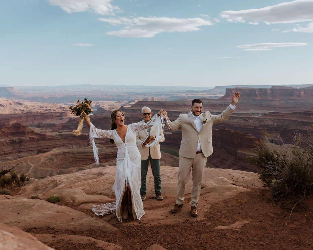 couple cheers holding hands at Dead Horse Point State Park Moab 