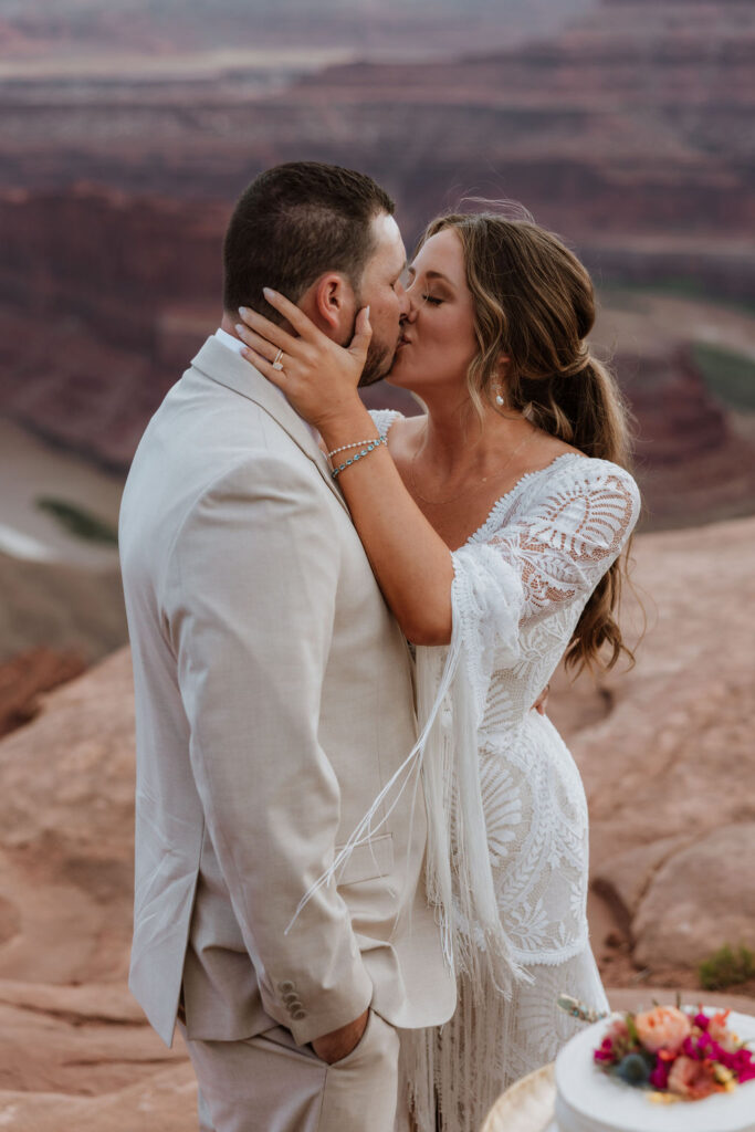 couple kisses on top of Moab overlook