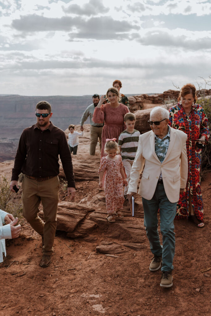 wedding guests walk to Moab elopement spot overlook