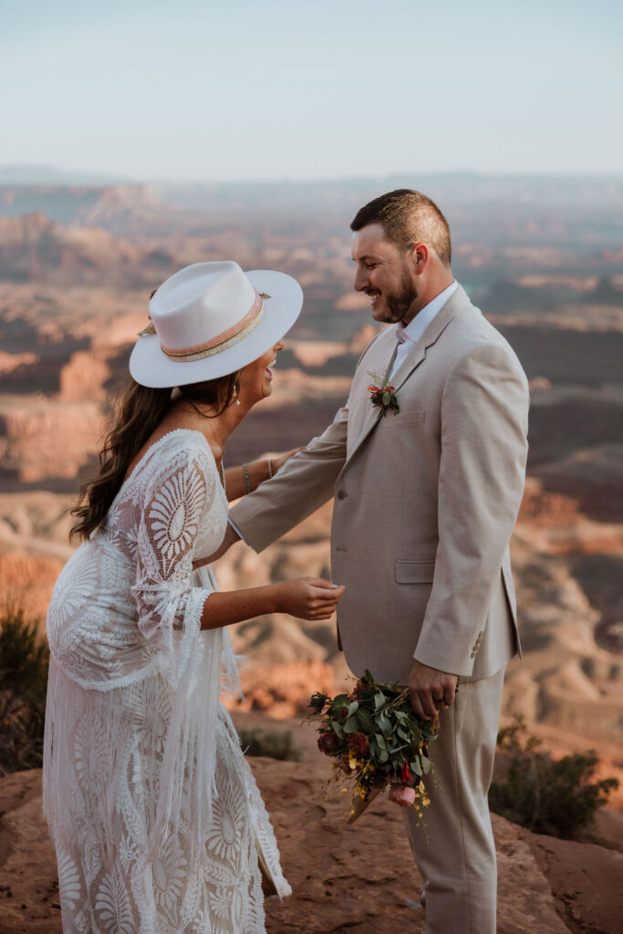 couple laughs while wearing hat at wedding first look