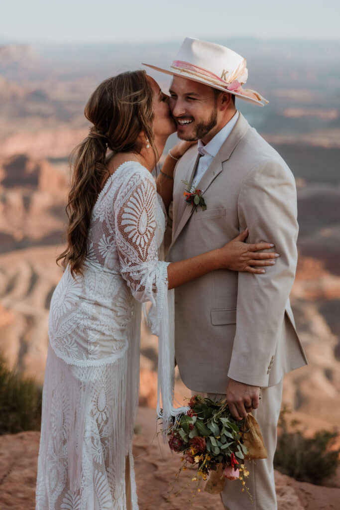 couple laughs while wearing hat at wedding first look