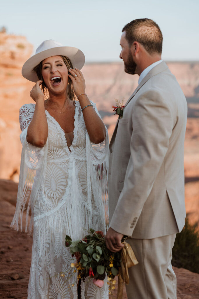 couple laughs while wearing hat at wedding first look